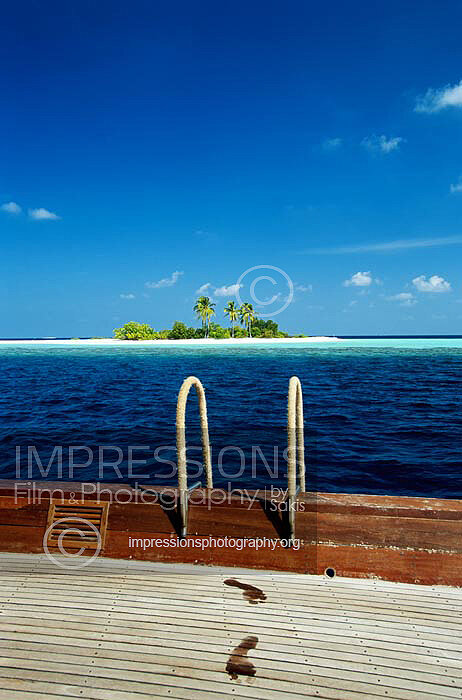 Maldives Traditional dhoni boat with wet footprints on wooden deck and tropical island
