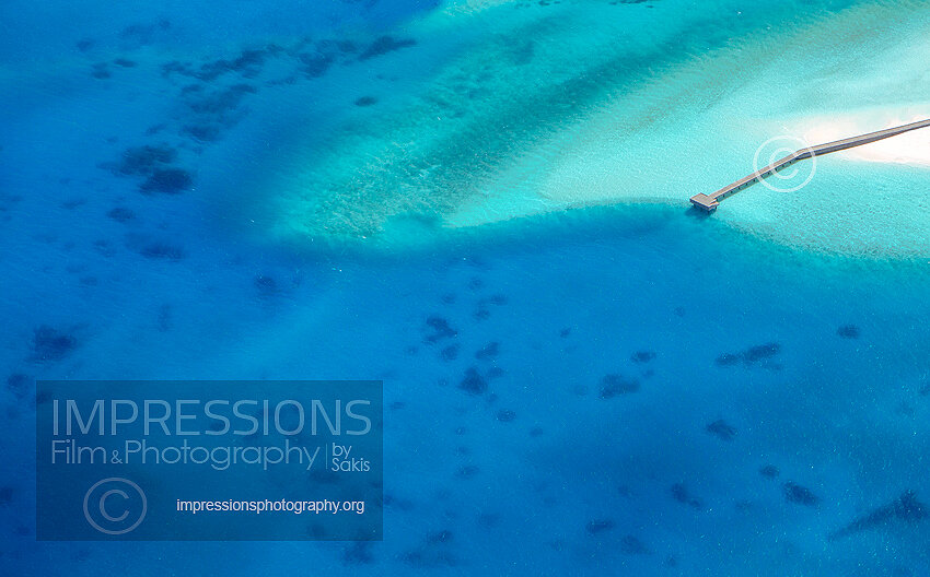 Maldives aerial view of wooden jetty out to tropical sea