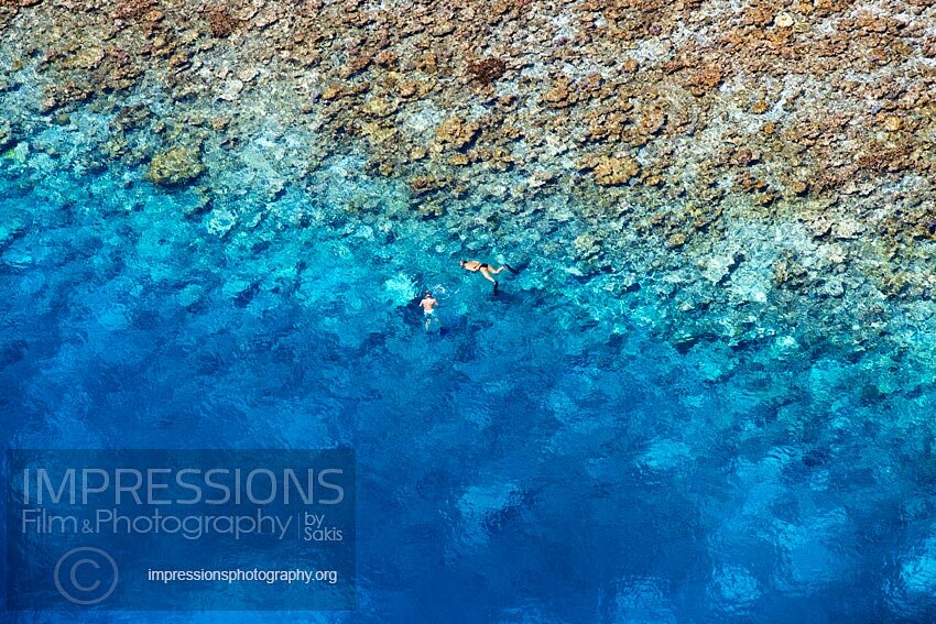 Maldives couple snorkeling on coral reefs aerial view stock photo