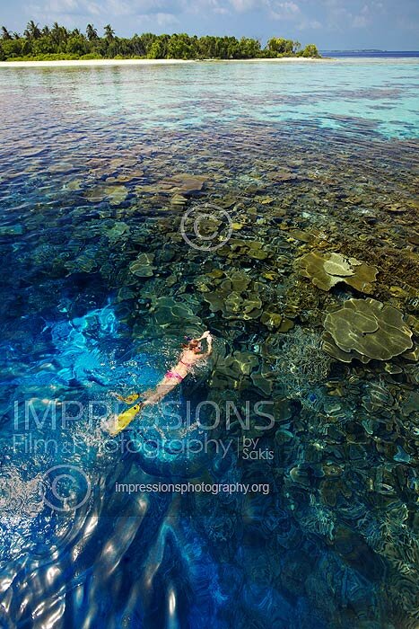 Maldives woman snorkeling on coral reefs and tropical island stock photo