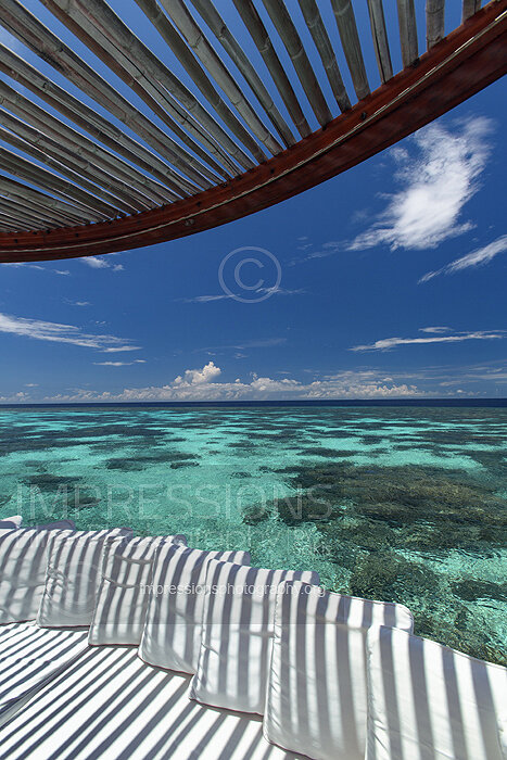 Maldives, deck of a water villa at Maldives resort with luxury sofa and lagoon with coral reefs and ocean view stock photo