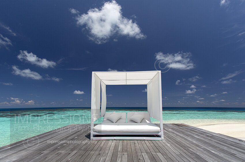 Maldives, wooden deck with luxury sofa and ocean view at beach stock photo