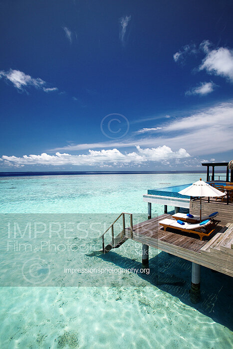 Maldives, deck of a water villa at resort with lounge chairs and sun umbrella with ocean view stock photo