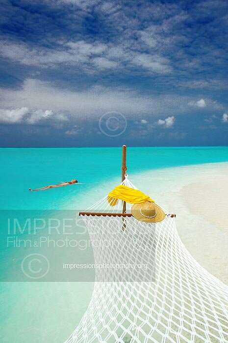 Hammock on the edge of a beach and woman swimming in lagoon