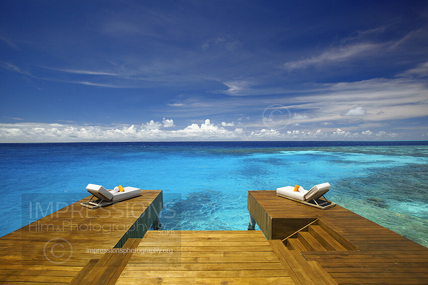 Maldives stock photo of luxury wooden deck with sun beds looking at the blue ocean and coral reefs