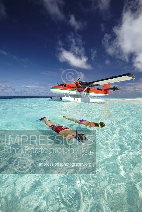 couple snorkeling in Maldives lagoon near a sandbank with seaplane