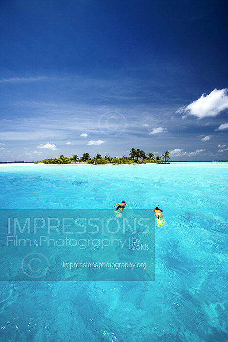 couple snorkeling in Maldives lagoon near a tropical desert island