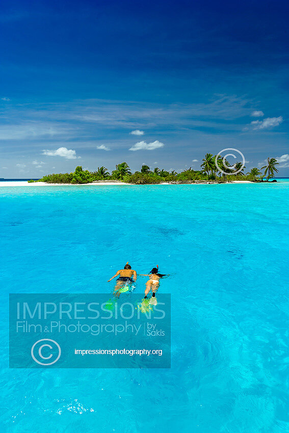 couple snorkeling in Maldives lagoon near a tropical desert island