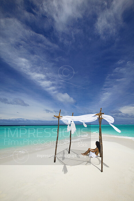 woman relaxing on a sandbank beach under a beach hut in Maldives