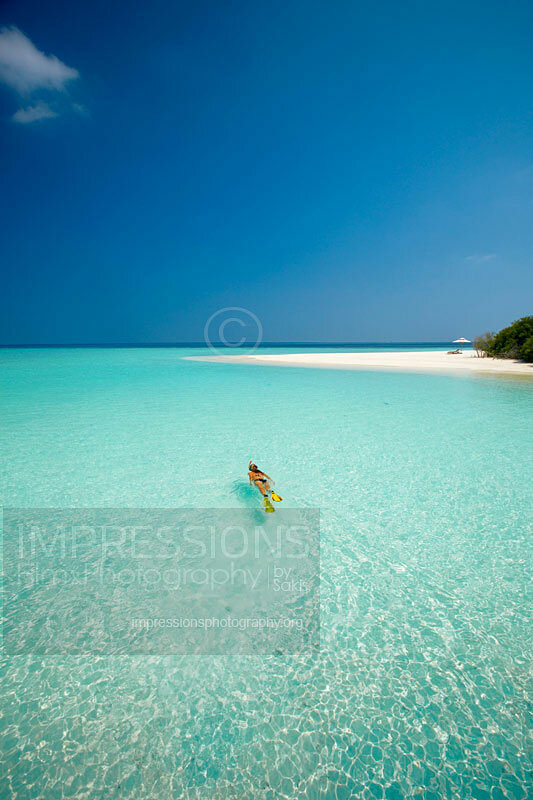 Young woman snorkelling in Maldives in blue lagoon with tropical desert beach Maldives stock photo