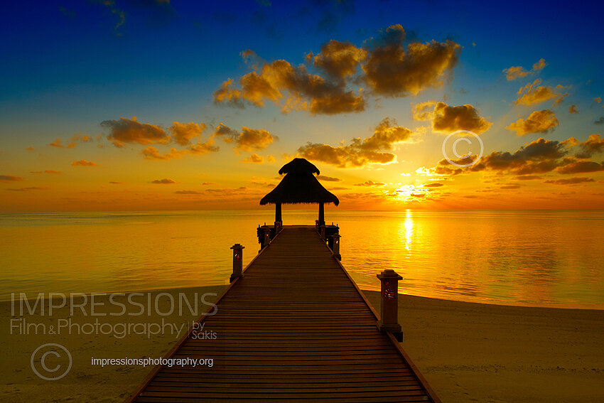 Maldives sunset with wooden jetty over ocean stock photo