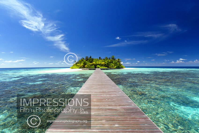 Maldives stock photo of a wooden jetty leading to a tropical island over blue lagoon and coral reefs