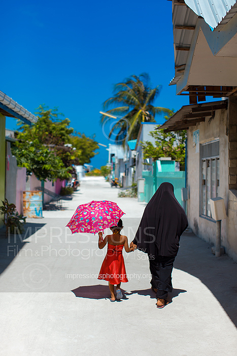 Mother and daughter walking together on local island, Maldives