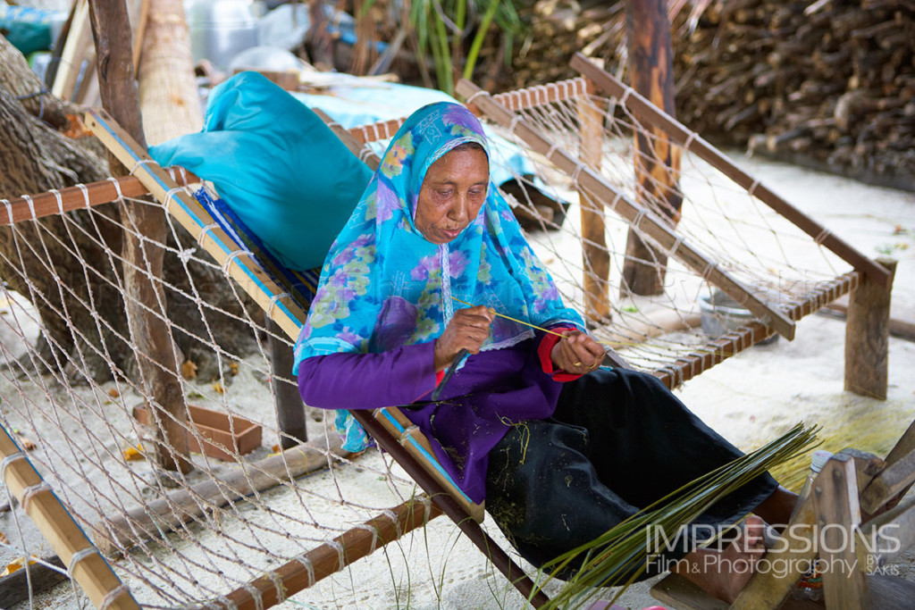 Lady in a joali preparing coconut leaves for ropes making on a Maldives local island