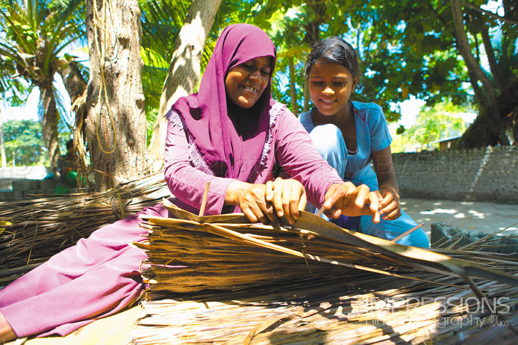 Maldives traditions a mother and daughter weaving coconut palms for kajan roofing